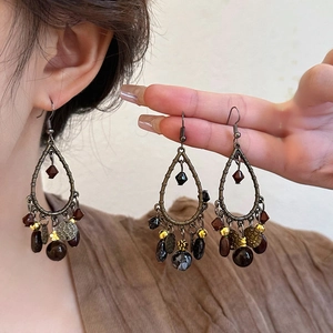 Macro shot of vintage bronze water-drop earrings with dangling beads and metal charms