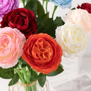 Close-up of realistic faux ranunculus silk flowers in a gold metal frame vase