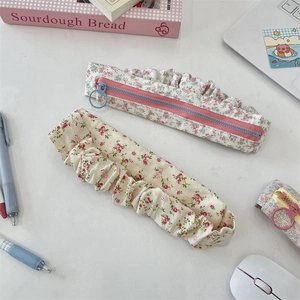 Floral fabric pencil case with matching scrunchie on a desk with stationery items