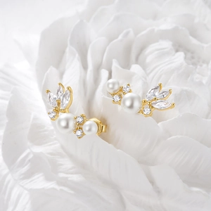 Detailed macro shot of gold pearl feather earrings with sparkling zircon leaf accents