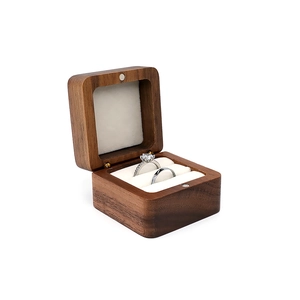 Double ring walnut wood box with white velvet lining showing engagement rings
