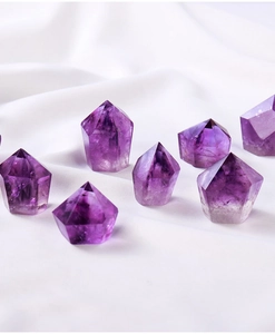 Macro shot of eight natural purple amethyst crystal hexagonal prisms on white silk fabric