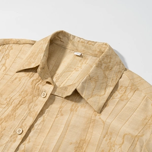 Macro detail of beige floral jacquard fabric and white buttons on a loose shirt