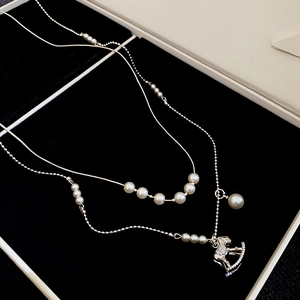 Close-up of a sparkling silver rocking horse pendant with pearls on a double-layer necklace