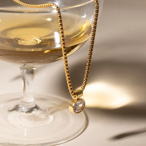 Classic 18K gold plated box chain necklace with egg-shaped zircon pendant on a glass