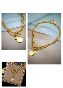 Dettaglio della collana multistrato vintage in acciaio al titanio dorato con ciondolo moneta