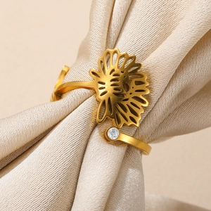 Macro shot of gold stainless steel open ring with petal design and zircon on silk