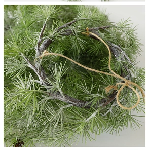 Close-up of artificial pine wreath featuring white frosted needles and natural jute rope