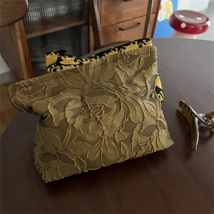 Detail of dark olive green jacquard makeup bag featuring floral relief embroidery