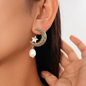Detailed close-up of a vintage crescent moon and star earring with a baroque pearl pendant