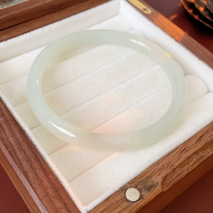 Close-up of light green jade bangle in round shape inside a wooden jewelry box