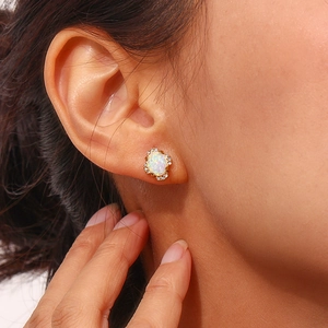 Close-up of gold-plated stainless steel stud earring with oval opal and diamond halo