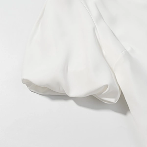 Détail de la manche bouffante en mousseline blanche avec tissu lisse et plis élégants
