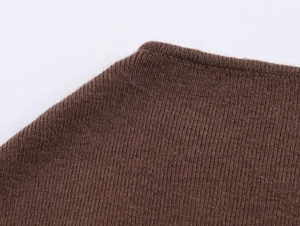 Macro shot of brown knitted fabric showing dense stitch texture and premium wool blend finish