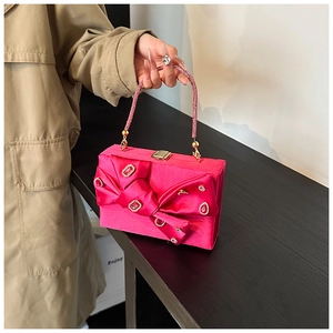 Detail of fuchsia evening clutch bag featuring a large bow and pink rhinestone accents