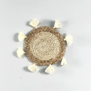 Detail of bohemian round straw wall decor with woven texture and white cotton tassels