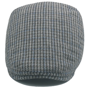 Detailed view of the wool tweed houndstooth fabric and blue check pattern of the flat cap