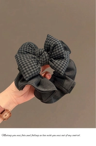 Détail d'un chouchou à nœud à carreaux noir et gris avec texture de tissu doux porté main
