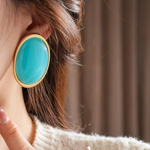 Nahaufnahme eines großen Vintage-Ohrrings aus türkisem Harz mit goldener Fassung