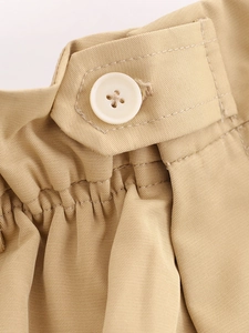 Détail de la taille en sergé kaki avec bouton en résine blanche et plis élastiques