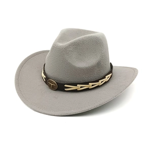 Detail of grey wool cowboy hat featuring a vintage bull head metal emblem and woven band