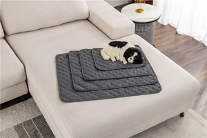 Close-up of quilted water-repellent grey pet mats in multiple sizes on a beige sofa