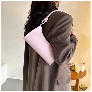 Close-up of pink baguette bag featuring knotted strap and smooth leather texture