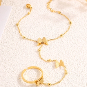 Golden butterfly titanium steel bracelet and ring set on minimalist beige background