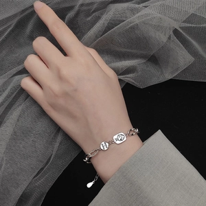 Detail of silver bunny pendant bracelet with NAU NAU engraving on a stylish mesh background