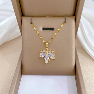Detail of maple leaf pendant in gold with white rhinestones on a beige jewelry box