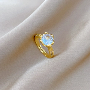 Gold plated adjustable ring with round zircon stone on champagne silk fabric background