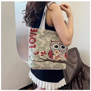 Detail view of ethnic owl tapestry on a woven canvas tote bag with floral embroidery