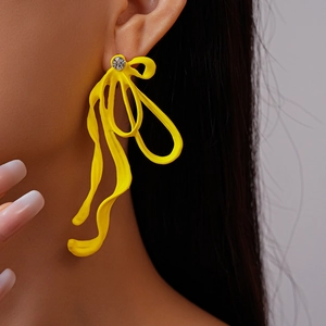 Detail of yellow tassel earrings with rhinestone stud shown on model in close-up view