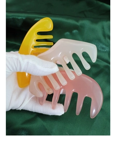 Scalp massage combs in yellow, white, and pink jade-like resin on green silk fabric