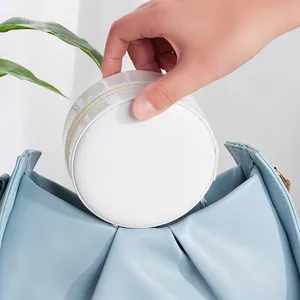 Portable white PU leather round jewelry box held in hand for travel convenience