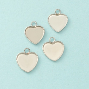 Close-up of four silver heart-shaped stainless steel pendant trays for DIY jewelry making