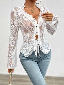 Close-up detail of white lace top with V-neck, lace-up front, and delicate ruffle trim