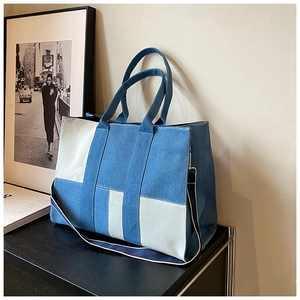 Detail of blue denim and white fabric tote bag with contrast shoulder strap
