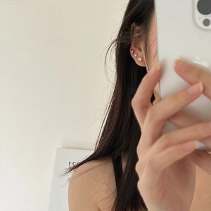 Close-up of minimalist gold zircon stud earrings worn on ear for a delicate jewelry look