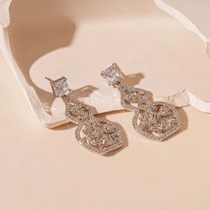 Detail of silver gourd earrings featuring hollow rose texture and square zircon stud