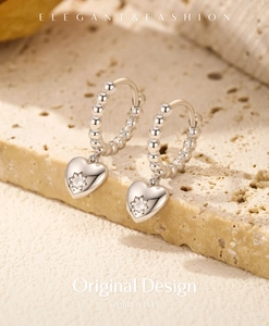 Detail of s925 silver heart charm earrings with zircon inlay on a textured stone base