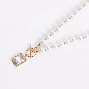 Detail of pearl necklace featuring gold OT toggle clasp and rectangle crystal pendant