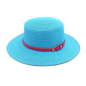 Close-up of bright blue flat top straw hat with magenta band and gold buckle detail