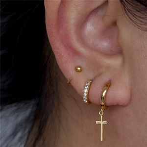 Detailed view of gold ear cuff set with cross pendant and cubic zirconia stud earrings