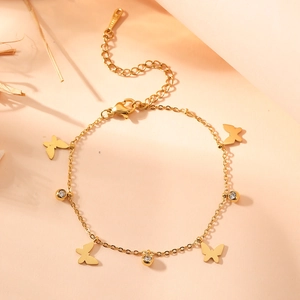 Elegant gold butterfly charm bracelet with sparkling crystals on warm natural background