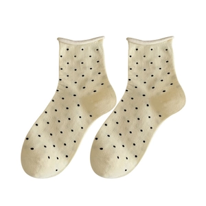 Chaussettes en tricot crème à pois noirs avec bord roulé sur fond blanc pur