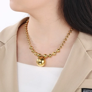 Detail of golden stainless steel ball necklace with a large bead pendant on model