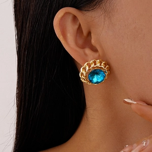 Detailed view of vintage gold chain earrings with a large blue oval gemstone on ear
