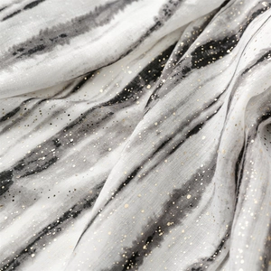 Detail of white cotton-linen scarf with black ink texture and golden glitter accents