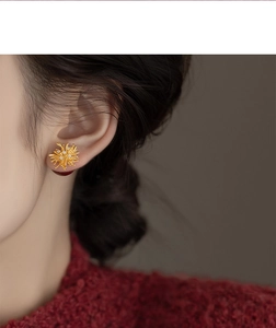 Close-up of gold coral flower earrings with white zircon on a model wearing red knitwear
